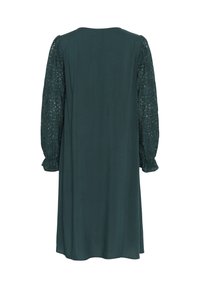 Mörkgrön klänning med en slät tygkropp och långa spetsärmar som har ett mönstrat mönster. Enkel, avslappnad passform med rund halsringning.
