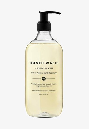 Klare Plastikflasche gefüllt mit einer hellgelben Flüssigkeit für die Handwäsche. Schwarzer Pumpenkopf und Etikett, das den Duft und Produktinformationen in schwarzer Schrift angibt.