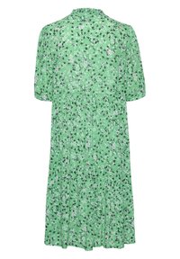 Robe florale verte avec un col rond, des manches courtes bouffantes, une jupe à volants et un tissu doux présentant des motifs de fleurs blanches et noires.
