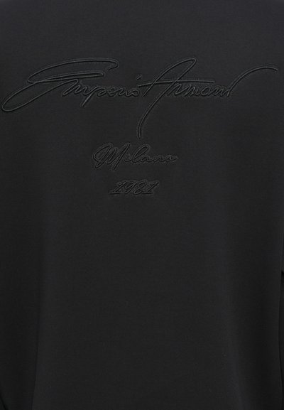 Svart sweatshirt med texturerad svart broderi av "Giorgio Armani Milano 1981" på baksidan, med en mjuk och slät tygtextur.