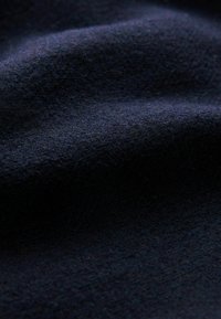 Marineblauwe stof met een zachte, licht textuur, die plooien en golvende bewegingen in het materiaal toont.