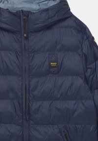 Granatowa kurtka puchowa wykonana z gładkiego, błyszczącego materiału; posiada poziome pikowanie, zamek z przodu i naszywkę z logo na klatce piersiowej.