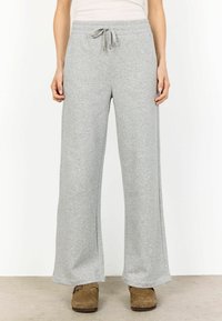 Pantaloni de trening gri deschis, cu o croială largă, confecționați dintr-un amestec moale de bumbac, având un elastic la talie cu șnur pentru o ajustare confortabilă.