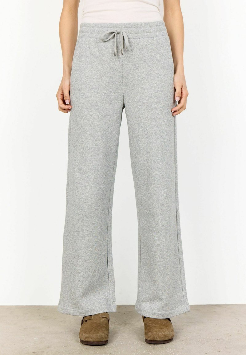 Pantaloni de trening gri deschis, cu o croială largă, confecționați dintr-un amestec moale de bumbac, având un elastic la talie cu șnur pentru o ajustare confortabilă.