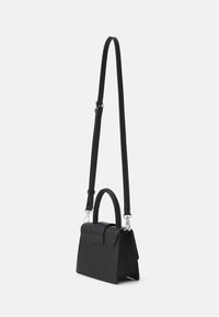 Sac à main noir structuré avec une poignée supérieure et une longue bandoulière réglable, présenté sur un fond blanc uni.
