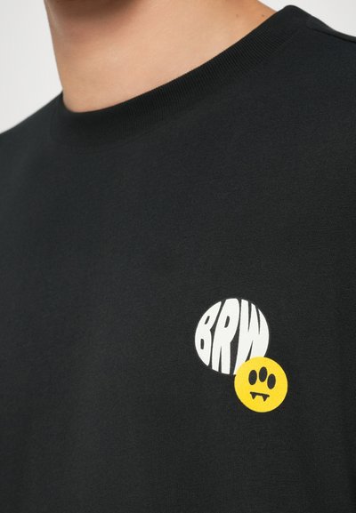 T-shirt in cotone nero con grafica bianca "BRW" e faccina sorridente gialla con zanne, colletto rotondo e texture morbida.