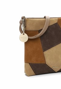 Suede handbag in a patchwork design featuring tan, brown, and beige sections. Includes a top handle and a circular metal tag.