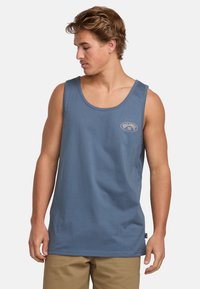 Top in cotone blu senza maniche con scollatura rotonda e piccolo logo ricamato sul petto. Orlo inferiore dritto e vestibilità rilassata.