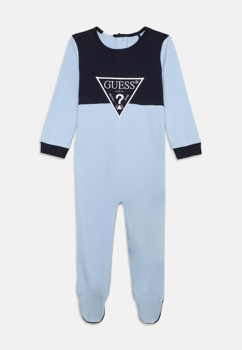 Blue and navy onesie with long sleeves, featuring a triangular Guess logo at the chest, soft cotton material, and footed design.