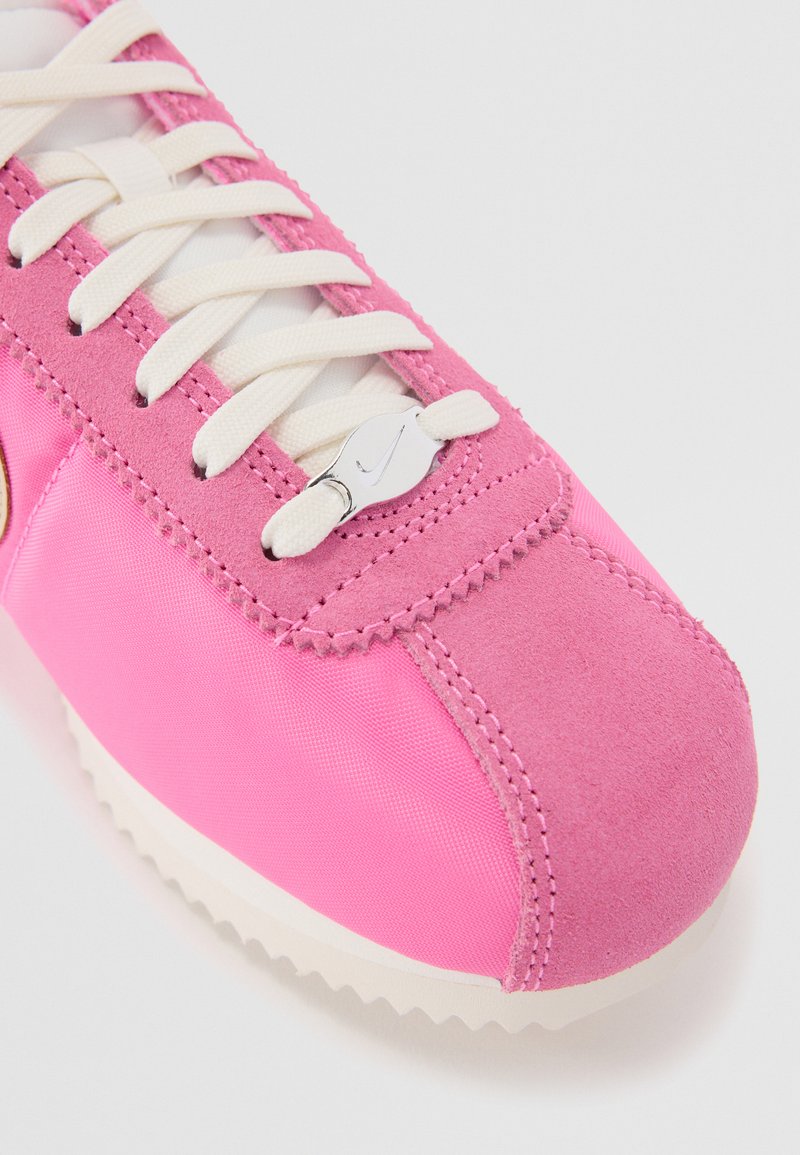 Rosa Sneaker mit einer Velourslederspitze und einem Obermaterial aus Nylon. Verfügt über weiße Schnürsenkel, einen metallischen Branding-Akzent und eine strukturierte Gummisohle.