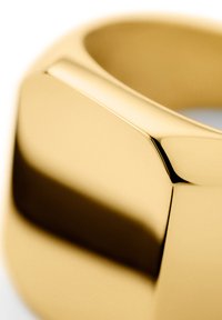Guldring med en glat, poleret overflade. Har vinklede kanter og et geometrisk design, der viser en reflekterende, skinnende finish.