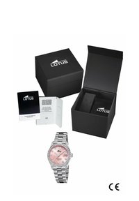 Montre Lotus avec un cadran rose, un bracelet en acier inoxydable et des accents en cristal. Présentée dans une boîte noire avec un livret et un autre compartiment.