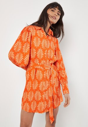 Abito camicia arancione con cintura in vita, caratterizzato da un motivo a foglie crema e maniche a palloncino, realizzato in tessuto leggero.