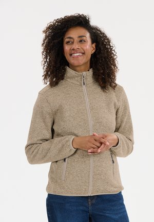 Chaqueta de forro polar beige con cremallera y cuello alto, bolsillos laterales y un patrón texturizado. El diseño presenta una tela suave y acogedora.