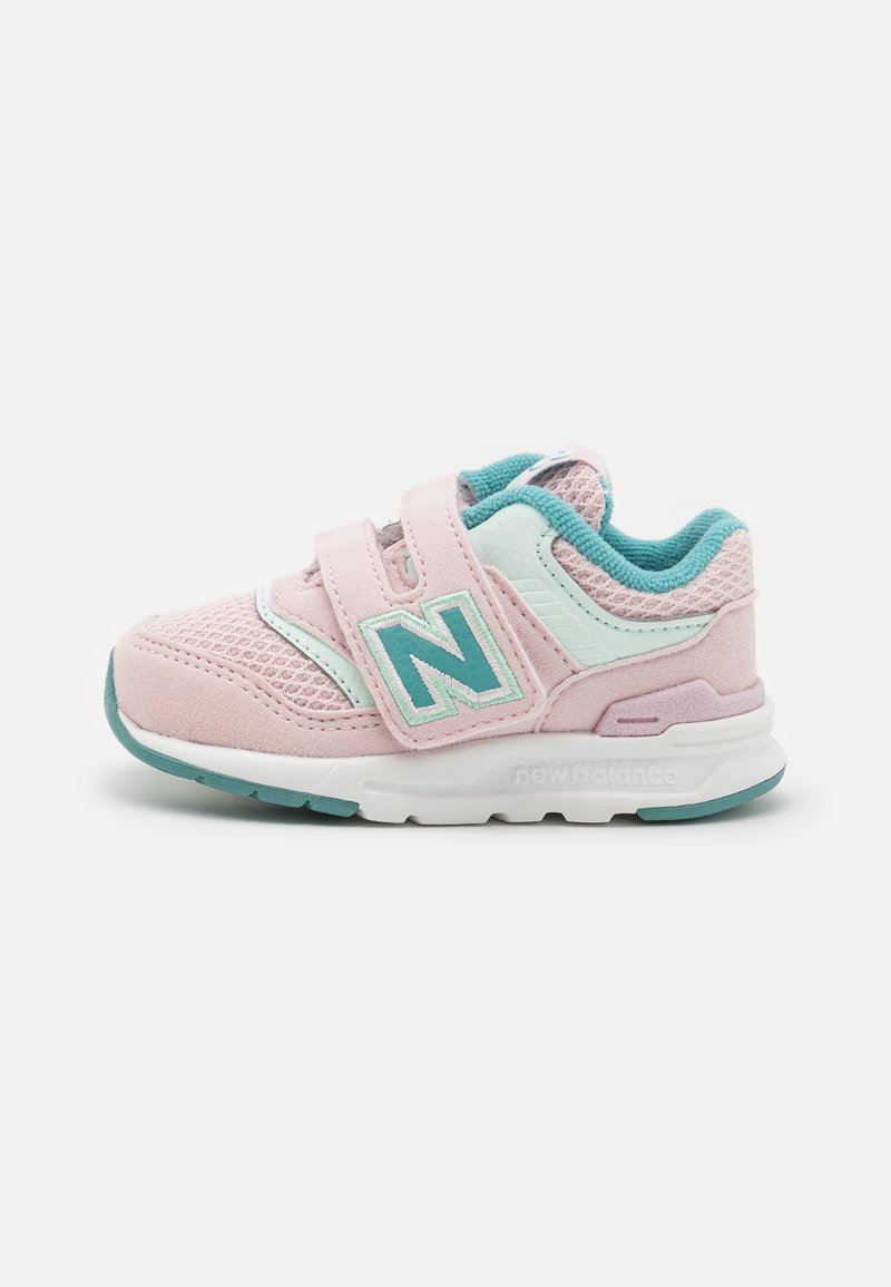 Light pink athletic shoe with mesh and suede materials, turquoise accents, adjustable straps, and a white outsole featuring branding.