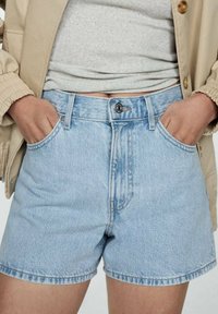 Shorts en denim bleu clair à taille haute, avec un bouton en métal et une conception à cinq poches. Texture légèrement déchirée et ourlets roulés.