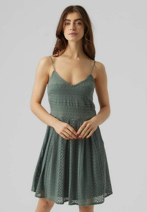 Green lace dress with adjustable spaghetti straps, fitted bodice, textured pattern, and flared skirt ending above the knee.