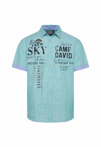 Korte mouw shirt in licht turkoois stof, met zwarte gedrukte tekst en accenten, en een contrasterende blauwe kraag en knoopsluiting.
