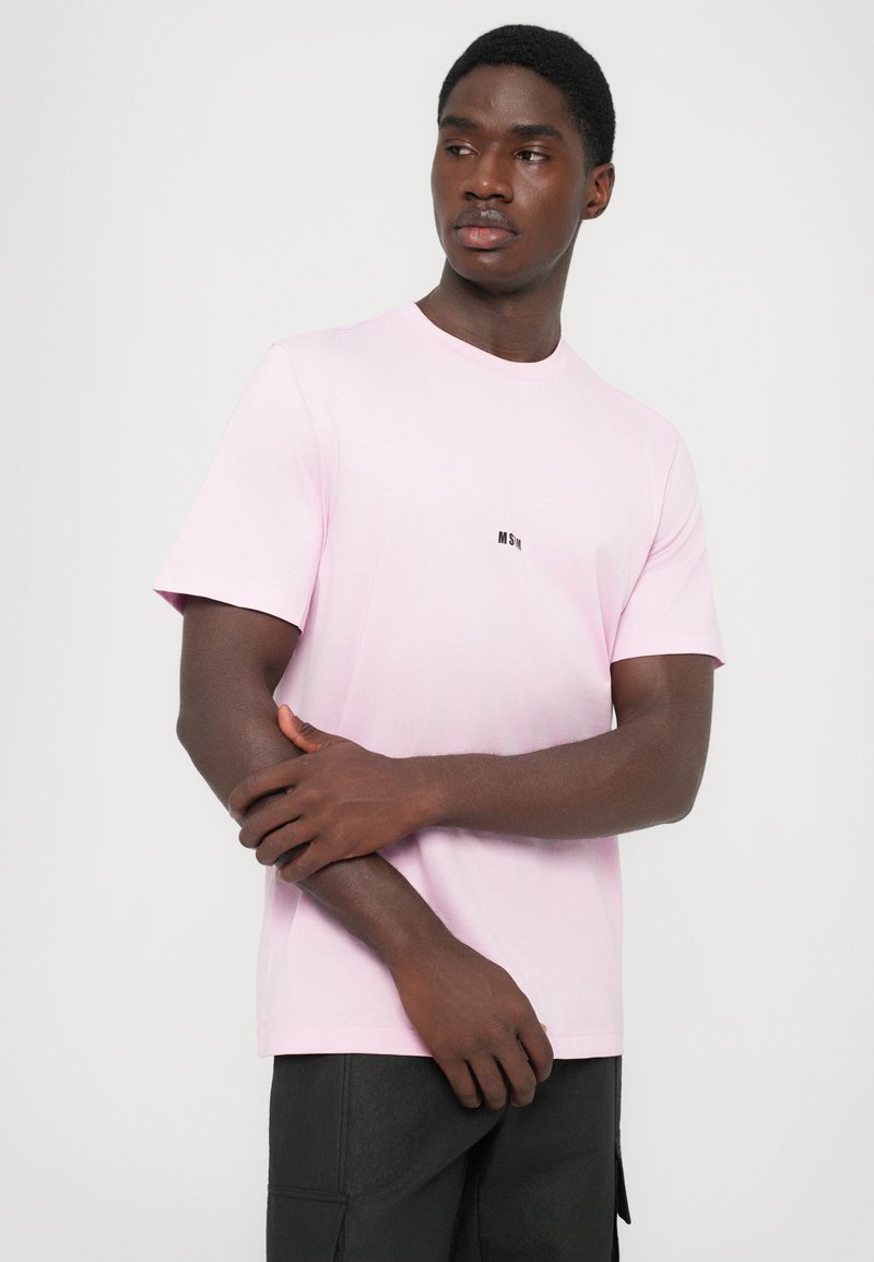 Pink bomuld t-shirt med korte ærmer, rund hals og et lille sort logo på brystet. Stoffet har en glat tekstur.