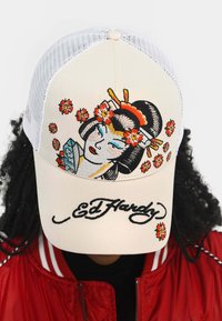Beige baseball cap with mesh back, featuring colorful embroidered geisha and flowers, and "Ed Hardy" script in black at the front.