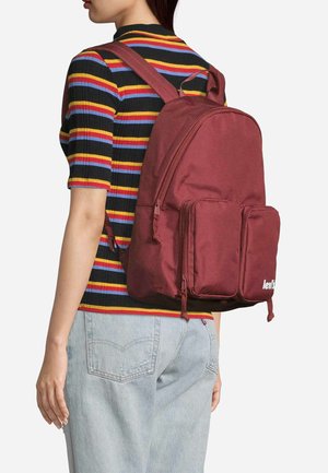 Mochila marrón hecha de un tejido duradero, con dos bolsillos frontales y correas ajustables. Presenta un logo en la parte frontal y cierres de cremallera.