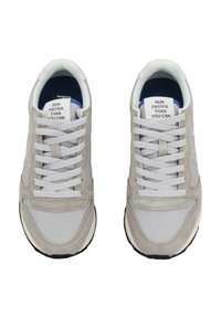 Zapatillas grises y blancas con parte superior de ante y malla, punta redonda, cordones blancos y una etiqueta que dice "CORRE MÁS RÁPIDO DE LO QUE PUEDES" en la lengüeta.