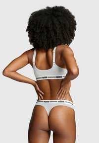 Grauer Sport-BH und passender String mit schwarzem "PUMA"-Logoband, aus weichem Material und mit minimalistischem Design.