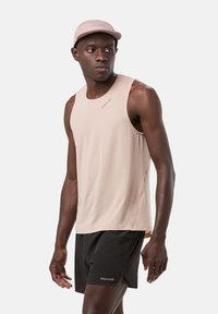 Light pink sleeveless tank top with a textured pattern, paired with black shorts. A pink cap completes the athletic look.