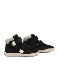 Bottines en daim noir avec deux bandes Velcro et un col rembourré gris. La semelle en caoutchouc présente un design texturé pour une meilleure adhérence.