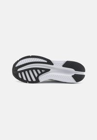 Semelle de chaussure de sport avec une section en caoutchouc noir texturé et une zone de rembourrage blanche. Comprend des rainures et des canaux pour une meilleure adhérence et flexibilité.