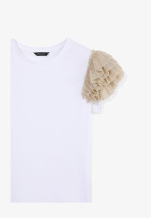 T-shirt bianca in cotone con dettaglio di balza beige texturizzata sulla spalla sinistra, con scollo rotondo e maniche corte.