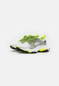 Zapatillas deportivas blancas y grises con cordones y acentos en verde brillante, una parte superior de malla texturizada y una suela gruesa negra con detalles en neón.