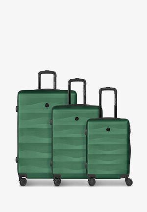 Trois valises rigides vertes de tailles petite, moyenne et grande avec poignées et roues noires, disposées côte à côte.