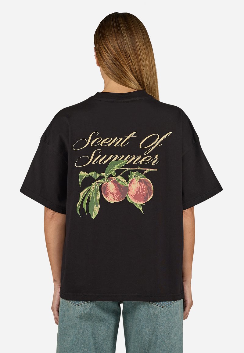 Zwarte oversized t-shirt met een perzikafbeelding met groene bladeren en de tekst "Scent Of Summer" in gouden script op de achterkant.