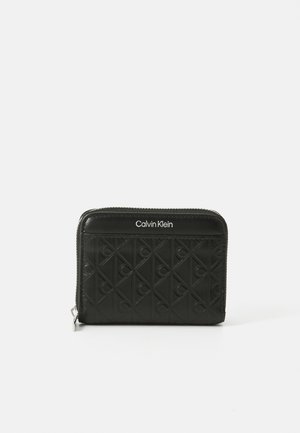 Black zippered wallet features embossed diamond pattern and Calvin Klein branding on the front. Made of smooth material. Compact and rectangular shape.
