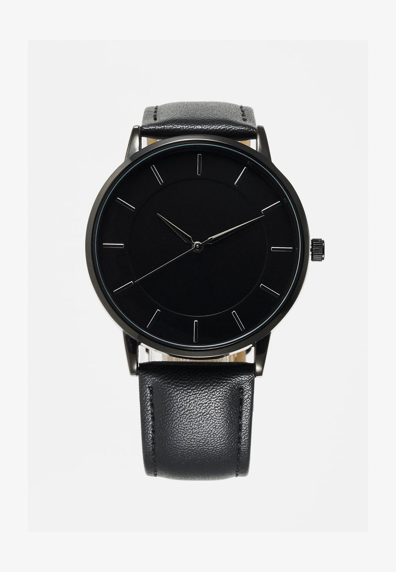 Black watch with a minimalist design, featuring a round face, silver hour markers, and a textured black leather strap. Silver crown on side.