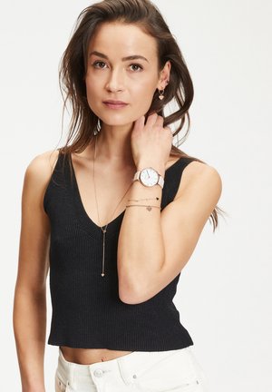 Schwarzes, gerippte, kurzes Tanktop mit V-Ausschnitt. Ergänzt durch mehrschichtige Schmuckstücke in黄金farbe und eine Uhr mit weißem Zifferblatt.