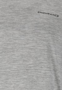Grå atletisk t-shirt i texturerad, fuktavledande tyg med en lätt heather-mönster och tryckt "ENDURANCE"-logotyp i svart.