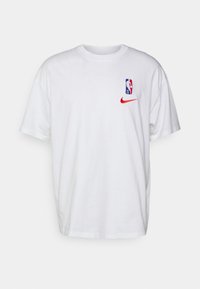 Camiseta blanca de algodón con mangas cortas, presenta un logotipo multicolor de la NBA y un logotipo rojo de Nike en el pecho.