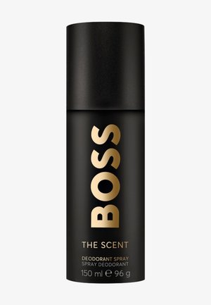Sort sylinderformet deodorantsprayboks med gullfarget "BOSS"-tekst, merket "THE SCENT", 150 ml, 96 g, mot hvit bakgrunn.