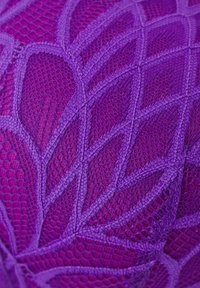 Tecido roxo com um padrão geométrico texturizado, com fios entrelaçados e áreas de rede aberta, exibindo variações em tonalidades de roxo.