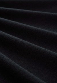 Tissu noir avec une texture douce et moelleuse, présentant des plis subtils et une surface lisse, mettant en avant sa couleur profonde et la qualité du matériau.