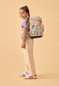 Multikleurige kinder rugzak met een roze en beige ontwerp, voorzien van stippenpatronen, buitenzakken en verstelbare schouderbanden.