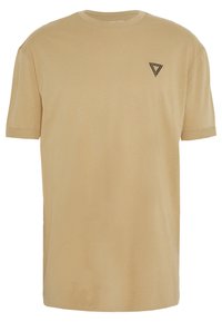 Camiseta de algodón beige con mangas cortas, escote redondo y un pequeño logo triangular negro en el lado izquierdo del pecho. Textura suave.