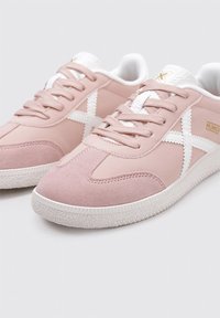 Sneaker in suede rosa con accenti bianchi, caratterizzate da un classico design con lacci e suola in gomma texturizzata. Cuciture e dettagli del logo distintivi.