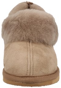 Pantoufle en suede beige avec un col doux et moelleux. Présente une texture lisse et un design de bout rond. Semelle en caoutchouc plate. Sans matériel ni motifs visibles.