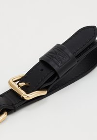 Cintura in pelle nera con fibbia in metallo dorato e dettaglio impresso. La cintura è liscia con bordi cuciti e un design elegante.