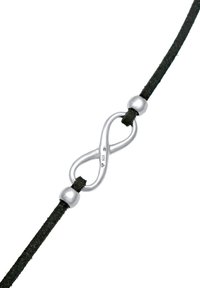 Sort suede snorarmbånd med en sølv uendelighedssymbol lås og metal accenter, der fremhæver et minimalistisk design.