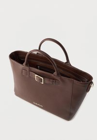 Bolsa tote de couro castanho com alças duplas, detalhe em fivela dourada e bolso interior com fecho. Textura suave e design aberto para fácil acesso.