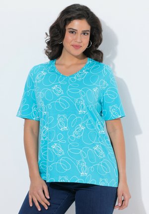 Frau trägt ein hellblaues V-Ausschnitt-T-Shirt mit weißem Bären- Linienkunstmotiv, steht vor einem schlichten weißen Hintergrund.